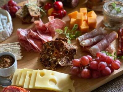 A picture from a charcuterie board party. The small charcuterie board contains a selection of meats, cheese and bread